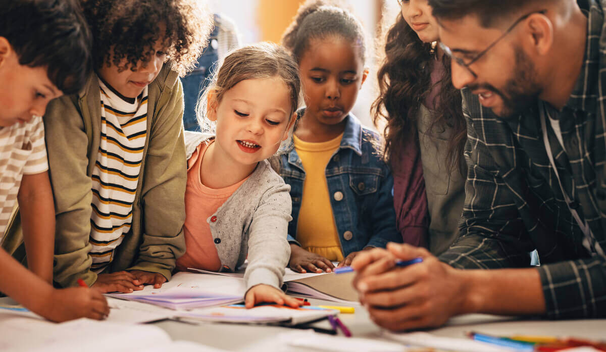 Students standing around a table with a teacher.